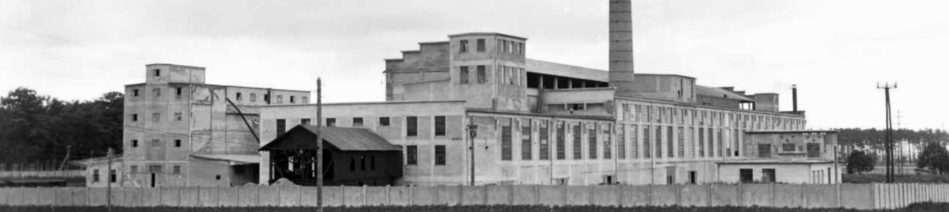 Historická čiernobiela panoráma stupavskej cementárne s výrobnými halami a komínom